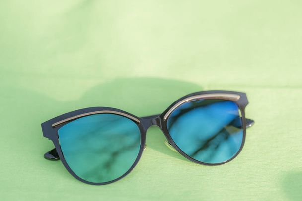 Cat Eye Sunglasses μοντέλο για γυναίκες με πολύ ιδιαίτερο σχεδιασμό και με μπλε φακούς πυροβολούν έξω σε μια καλοκαιρινή μέρα. Επιλεκτική εστίαση  - Φωτογραφία, εικόνα