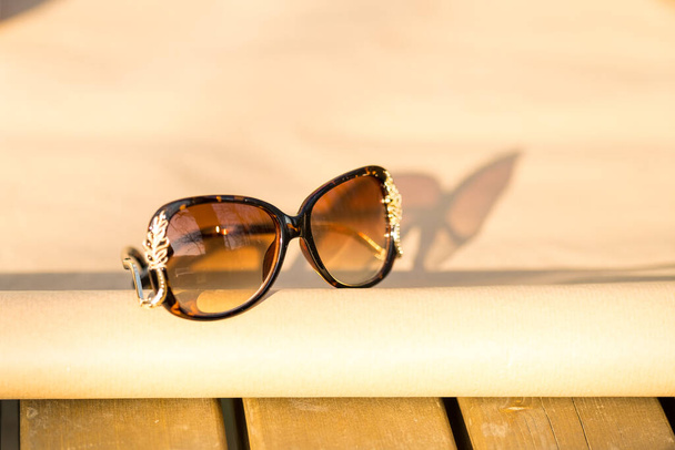 Γυαλιά ηλίου καφέ χρώμα μοντέλο για τις γυναίκες με ένα ειδικό σχεδιασμό πυροβολούν έξω στη φύση σε μια καλοκαιρινή μέρα. Επιλεκτική εστίαση  - Φωτογραφία, εικόνα