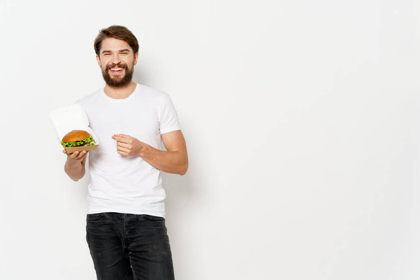 mies valkoisessa t-paidassa hampurilainen pikaruokaa ruokavalio välipala - Valokuva, kuva