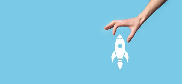 Egy férfi kézben tartja a rakéta ikonját, ami felszáll, és kék háttérrel indít. rakéta indul és repül ki, Business start up, Icon marketing a modern virtuális felületen.Start up koncepció - Fotó, kép