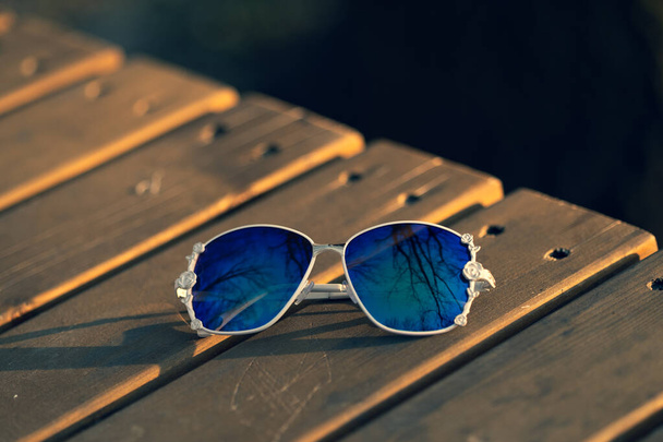 Модна модель сонцезахисних окулярів з великими блакитними лінзами для жінок зі спеціальною дизайнерською стрічкою зовні в природі в літній день. Вибірковий фокус
  - Фото, зображення