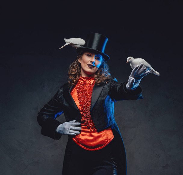 Vrouwelijke artiest met krullend haar toont een magische truc met duiven - Foto, afbeelding