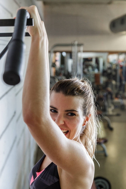 Young happy woman working her arms muscles in the Gym - Photo, Image