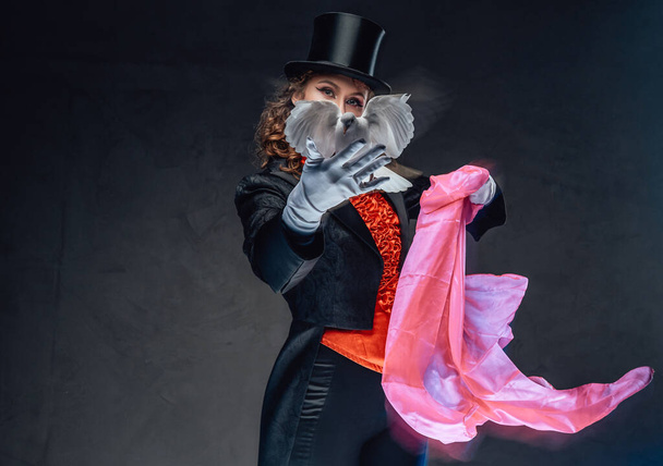 Активная колдунья показывает фокусы с птицей и розовым шарфом - Фото, изображение