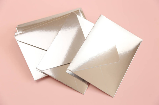 Spiegelpapier feestelijke enveloppen op roze achtergrond, bovenaanzicht. Enveloppen voor uitnodigingen of kadootjes. - Foto, afbeelding