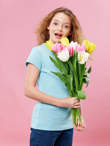 girl with curly hair bouquet of flowers fun pink background holiday - Photo, Image