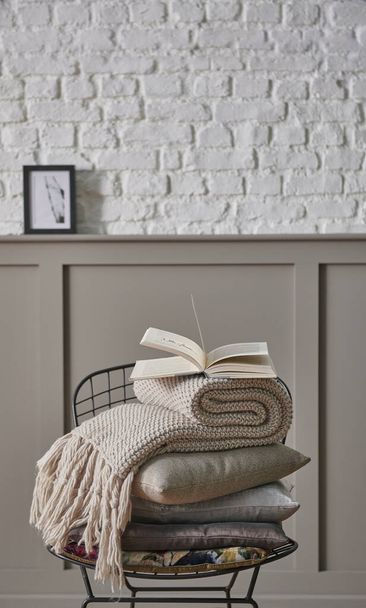 Pillow and blanket folding on the black metal chair, classic brown wall and white brick wall background home object still life concept. - Photo, Image