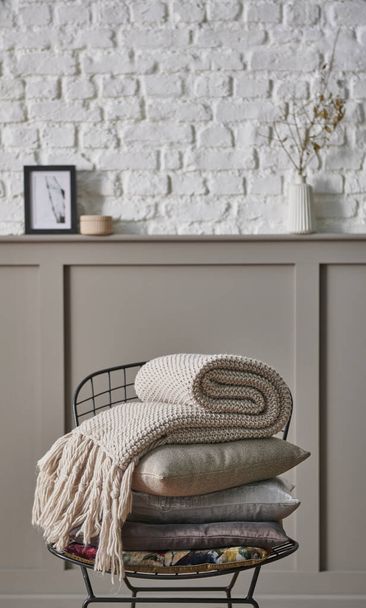 Almohada y manta plegable en la silla de metal negro, pared marrón clásico y fondo de pared de ladrillo blanco hogar objeto naturaleza muerta concepto. - Foto, Imagen