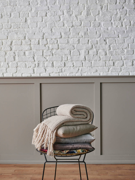 Almohada y manta plegable en la silla de metal negro, pared marrón clásico y fondo de pared de ladrillo blanco hogar objeto naturaleza muerta concepto. - Foto, Imagen