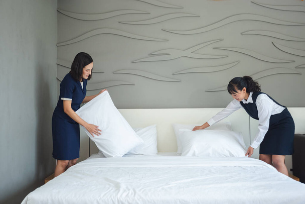 Zwei asiatische junge Frau Zimmermädchen machen Bett und Kissen im Hotel. Personal Zimmer Hotel Service.  - Foto, Bild