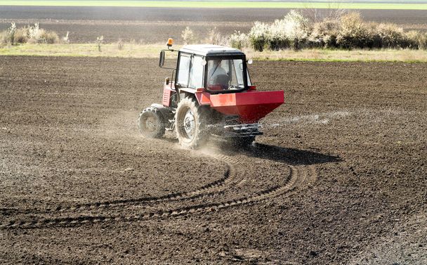 畑に人工肥料を広げるトラクター - 写真・画像