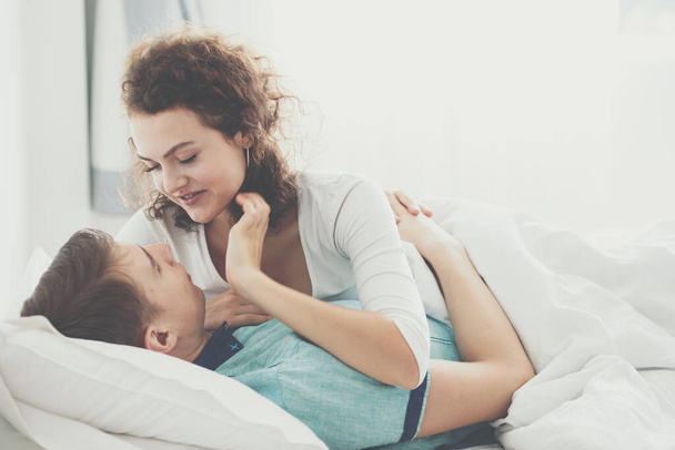 Beautiful couple lying together on the bed loving couple in morning wake up - Фото, изображение