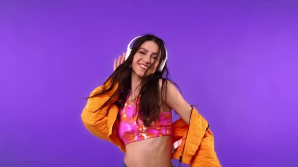 Bailarina sonriente en auriculares aislados en púrpura  - Imágenes, Vídeo