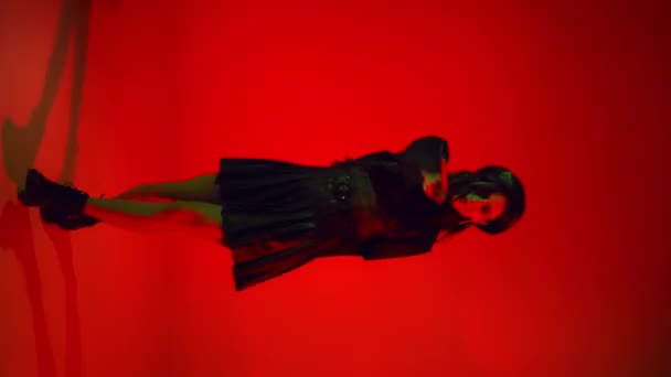 Γυναίκα με φούστα και μπερέ χορεύει σε κόκκινο φόντο με φωτισμό  - Πλάνα, βίντεο