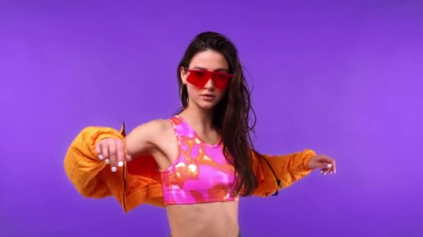 Mujer con estilo en gafas de sol con chaqueta aislada en púrpura  - Imágenes, Vídeo