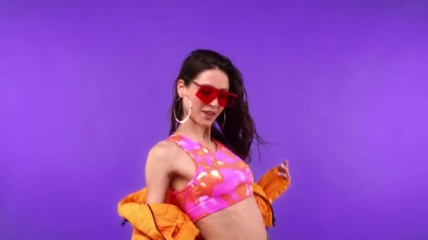 Stylowa kobieta w okularach przeciwsłonecznych tańczy na fioletowym  - Materiał filmowy, wideo
