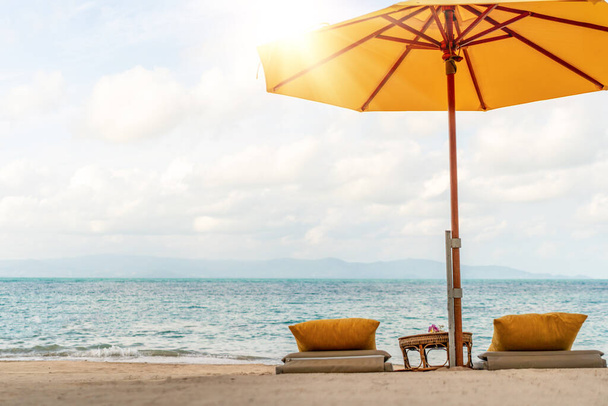 Paraplu en stoel op tropische zomer strand achtergrond met kopieerruimte blauwe lucht. - Foto, afbeelding