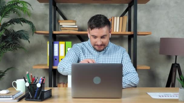 Glimlachende man zit op stoel aan het bureau in het kantoor thuis open en beginnen met behulp van laptop - Video
