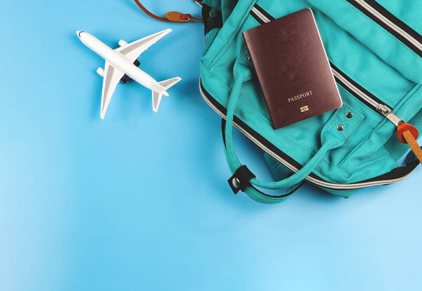 Вид сверху или плоский слой паспорта, зеленый рюкзак и модель самолета на синем фоне. Концепция путешествия. - Фото, изображение