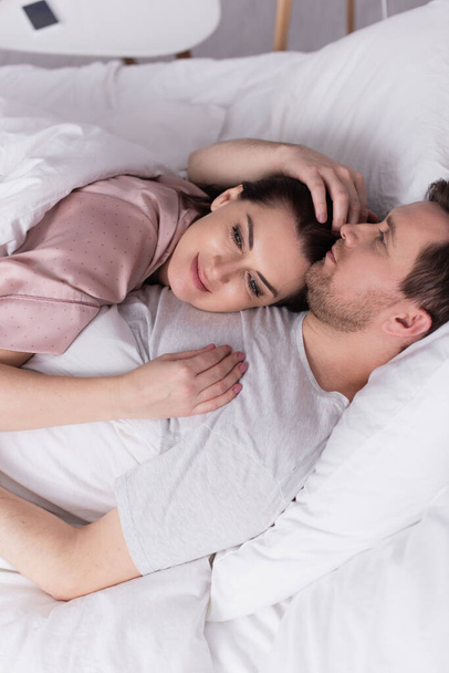 Adult woman lying on chest of husband on bed  - Photo, image