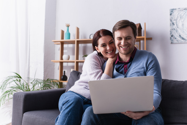 Couple adulte heureux en utilisant un ordinateur portable sur le canapé  - Photo, image
