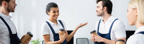 Усміхнений афроамериканський прибиральник тримає каву, щоб піти поруч з колегами в офісі, банер
  - Фото, зображення