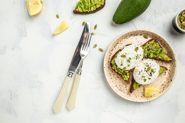 Avocado Sandwich with Poached Egg and avocado on toasted bread. Delicious breakfast or snack on a light background, top view. - Photo, Image
