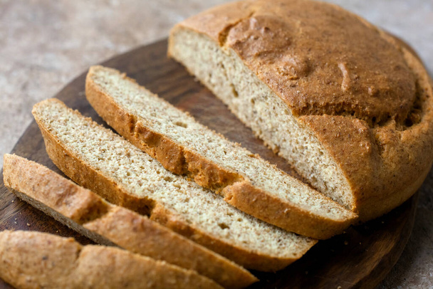 Homemade almond Low carb ketogenic bread with bran and fiber on plate, Wooden Cutting Board with knife, light linen napkin on beige stone concrete background. glutenfree vegetarian food concept. - Photo, Image