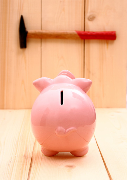Hauska vaaleanpunainen säästöpossu painopiste ja vasara puuta
 - Valokuva, kuva