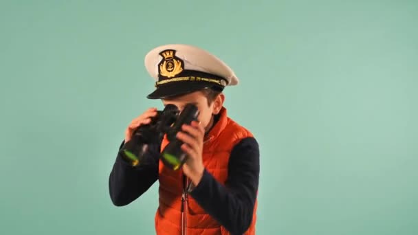 Il giovane capitano marinaio guarda qualcosa in mare. sfondo ciano - Filmati, video