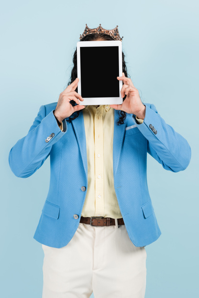 άνδρας σε σακάκι και στέμμα που καλύπτει το πρόσωπο, ενώ κρατώντας ψηφιακή ταμπλέτα με λευκή οθόνη που απομονώνονται σε μπλε - Φωτογραφία, εικόνα