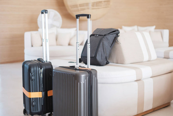 Dos maletas negras o una maleta en un hotel moderno durante el registro de entrada. Tiempo para viajar, servicio, viaje, viaje, vacaciones de verano y conceptos de vacaciones - Foto, Imagen