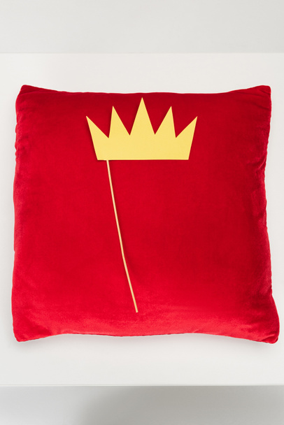vrchní pohled na papírovou korunu na tyčce a červený sametový polštář na šedé - Fotografie, Obrázek