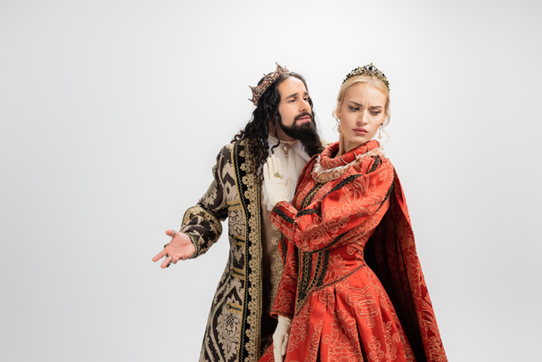 hispánský král v koruně a středověké oblečení při pohledu na blond manželka ukazuje stop gesto izolované na bílém - Fotografie, Obrázek