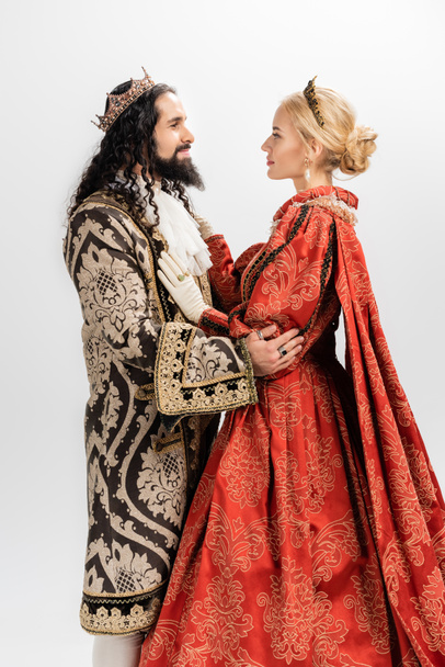 interrazziale re e regina in abiti medievali e corone abbracci isolati su bianco - Foto, immagini