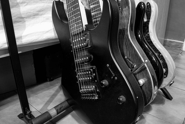 Zwei Gitarren und zwei Bässe auf einem Mehrfuß in schwarz-weiß - Foto, Bild