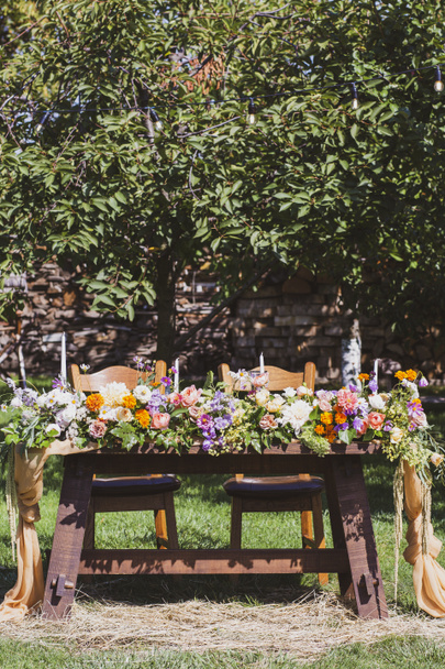 Banketové stoly v přírodě. Svatba na zahradě. Venkovní svatba. Bufet. Svatební hostina v přírodě.Slavnostní stůl servírující jídla stojí na zelené trávě. stolní kompozice, sklenice, svíčky a talíře jsou umístěny na stůl - Fotografie, Obrázek