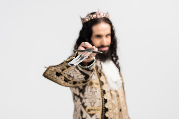 hispanic king in medieval clothing and crown holding blurred sword isolated on white - Photo, Image