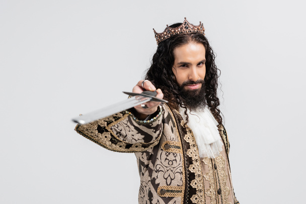 rey hispano en ropa medieval y corona sosteniendo espada borrosa aislada en blanco - Foto, imagen