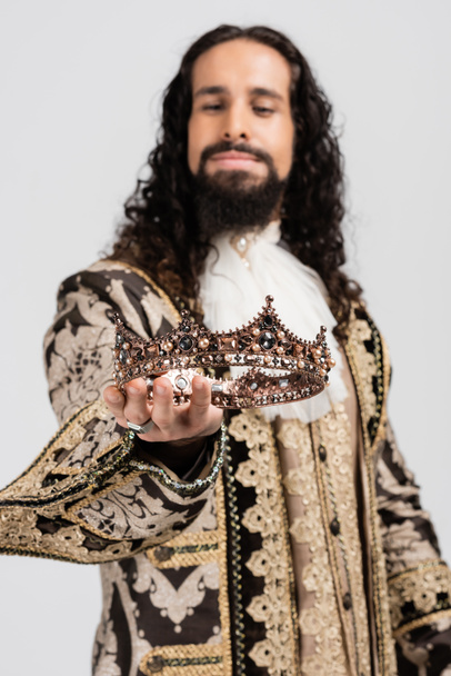 blurred hispanic king in medieval clothing holding crown isolated on white - Photo, Image