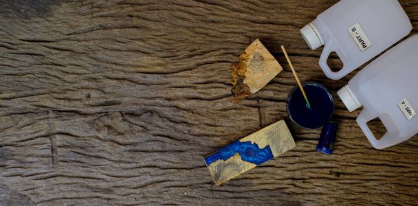 Houten burl houtsnippers kleur fles en hars epoxy voor het gieten van hout op oude houten tafel achtergrond - Foto, afbeelding