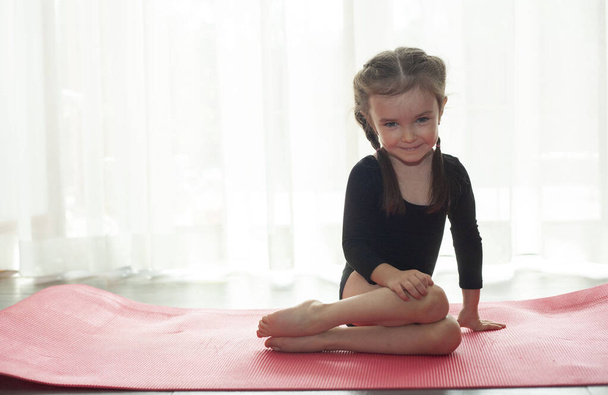 Little girl doing gymnastic exercise. Girl doing yoga at home - Zdjęcie, obraz