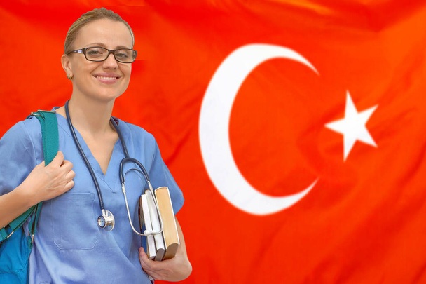 Doktorandin mit Stethoskop und Büchern in der Hand auf dem Hintergrund der türkischen Flagge. Medizinisches Ausbildungskonzept. Medizinisches Lernen in der Türkei - Foto, Bild