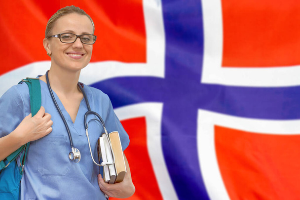 Medico studentessa con stetoscopio e libri in mano sullo sfondo bandiera norvegese. Concetto di educazione medica. Imparare medicina in Norvegia - Foto, immagini
