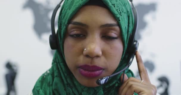 Close up of happy Islamic businesswoman with hijab wearing a headset while standing in the modern office - Filmati, video