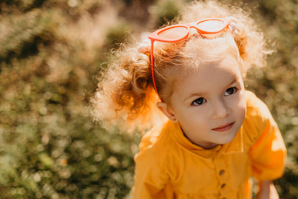 Portrait photos caucasian kid girls aged 2 to 4 years with curly hair, cute face, smiling, who looks up at the person who is photographing her - Foto, Imagen