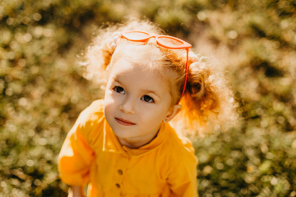 Portrait photos caucasian kid girls aged 2 to 4 years with curly hair, cute face, smiling, looking healthy and cute, with green bokeh background - Foto, Bild