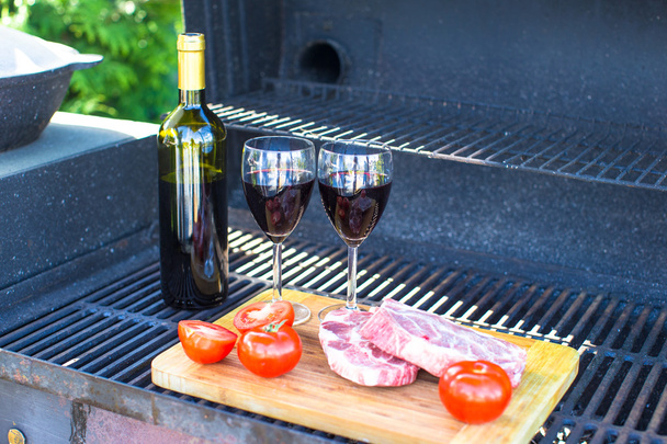 Свіже м'ясо, овочі та пляшка вина на пікніку на відкритому повітрі
 - Фото, зображення