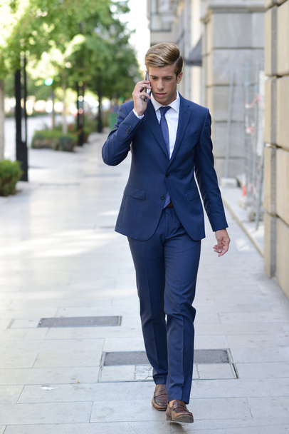 Attractive young businessman on the phone in urban background - 写真・画像
