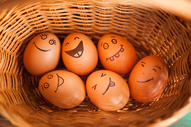 Stack of eggs with hand drawn faces on straw basket, easter preparation, holiday mood concepts - Photo, Image